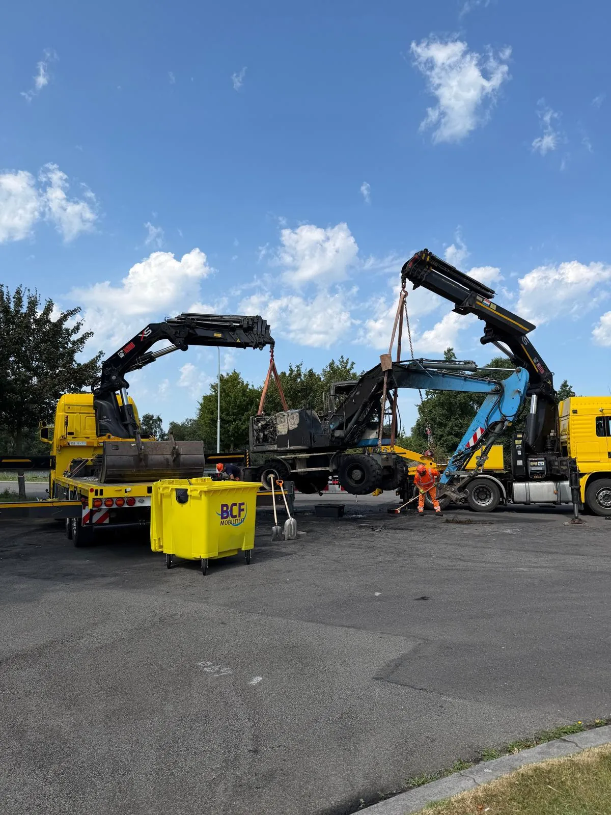 Two BCF Mobiliteit crane trucks lifting a machine together
